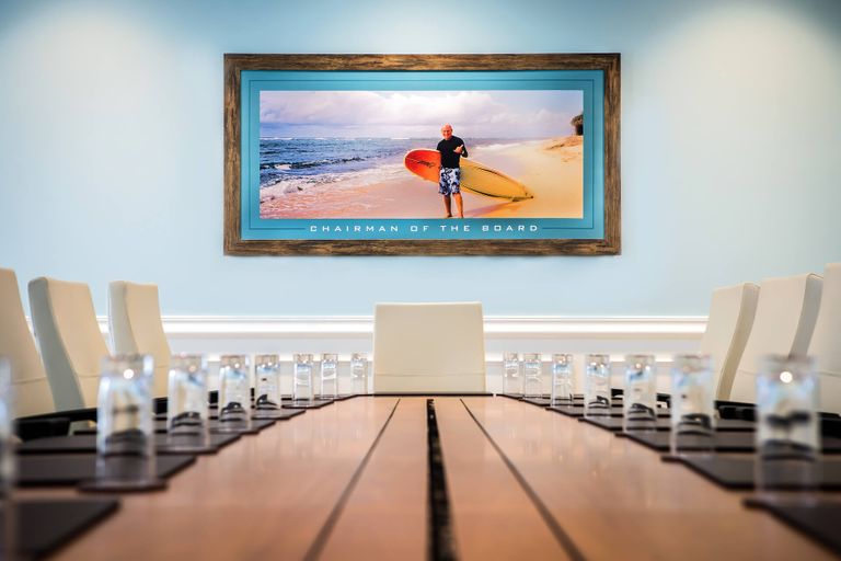 مكان للاجتماعات في Margaritaville Resort Orlando يعرض صورة مؤطرة لجيمي بافيت وهو يحمل لوح تزلج على الماء على الشاطئ مع تسمية توضيحية تقول "رئيس مجلس الإدارة".