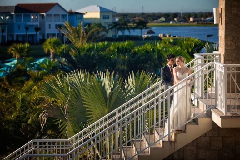 العروس والعريس يقفان أمام الكاميرا على درج في Margaritaville Resort Orlando.