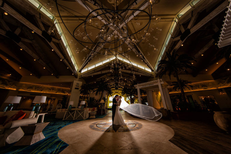 العروس والعريس يتعانقان في وسط بهو فارغ في Margaritaville Resort Orlando.