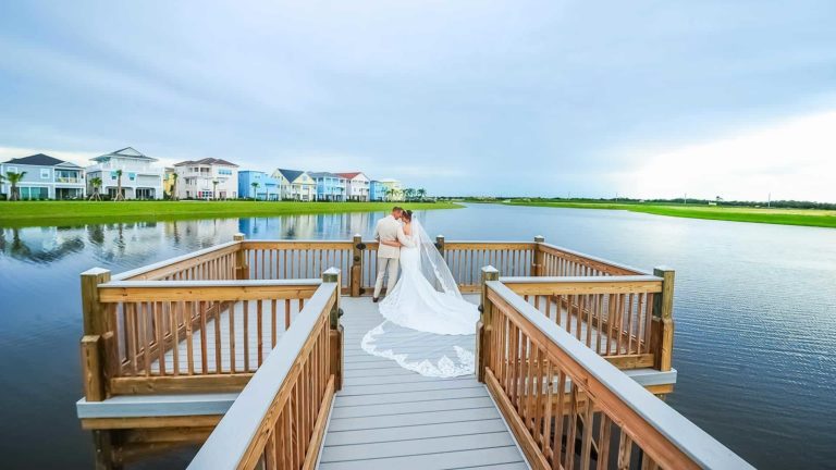 يقف العروس والعريس على رصيف يطل على البحيرة في Margaritaville Resort Orlando.
