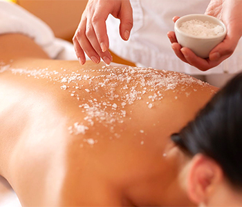 Woman lying down during a spa treatment with sugar scrub on her back.