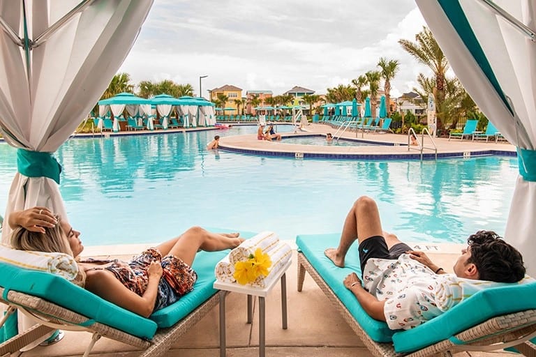 زوجان يسترخيان في كابانا بجانب المسبح في Margaritaville Resort Orlando. تجربة جميلة