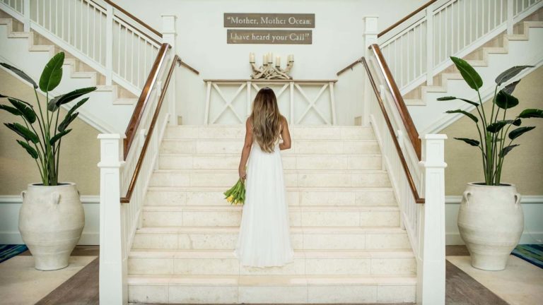 العروس تحمل باقة زهور على الدرج في Margaritaville Resort Orlando.