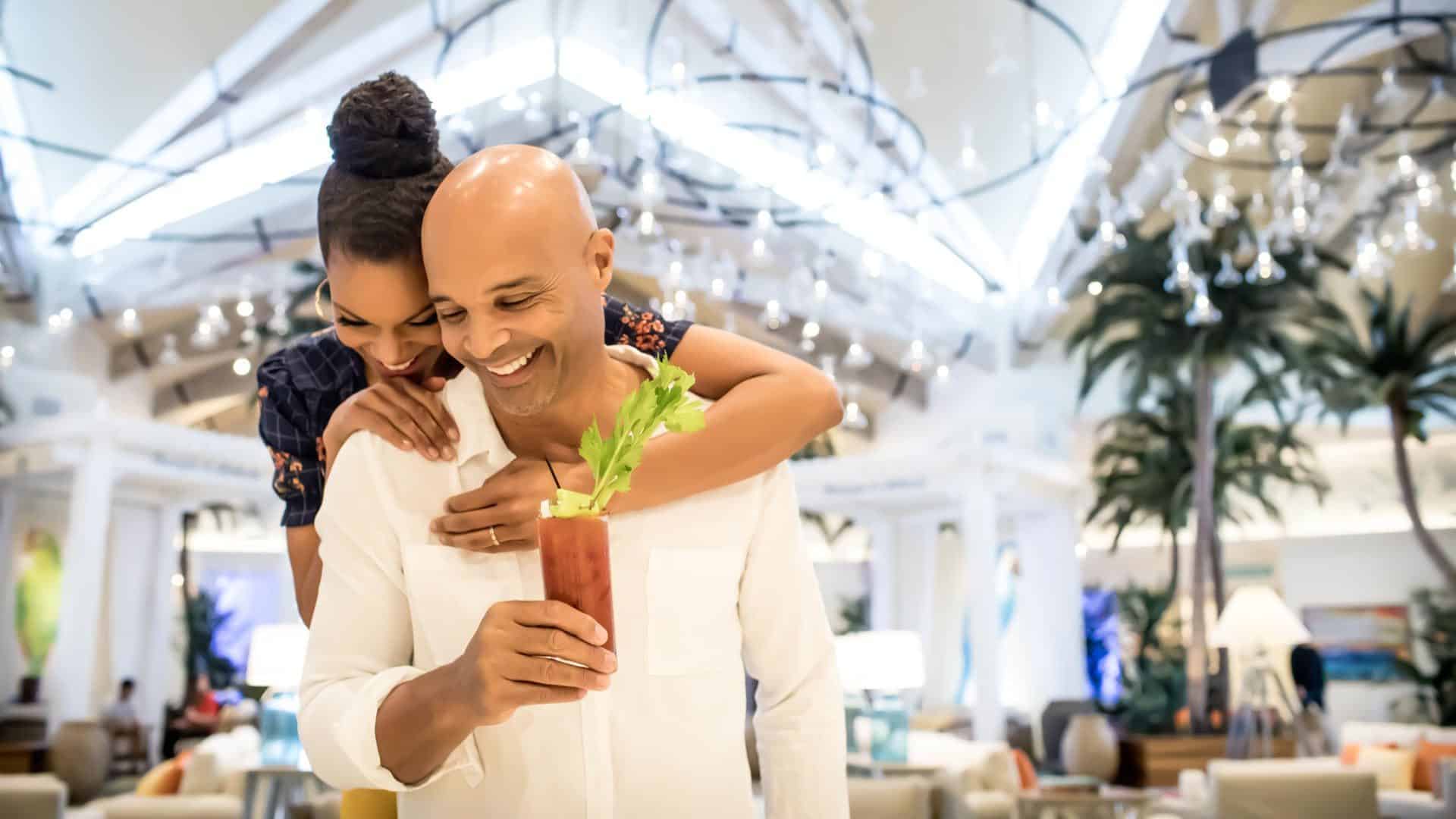 Marido e mulher se abraçando e sorrindo no saguão do Margaritaville Resort Orlando.