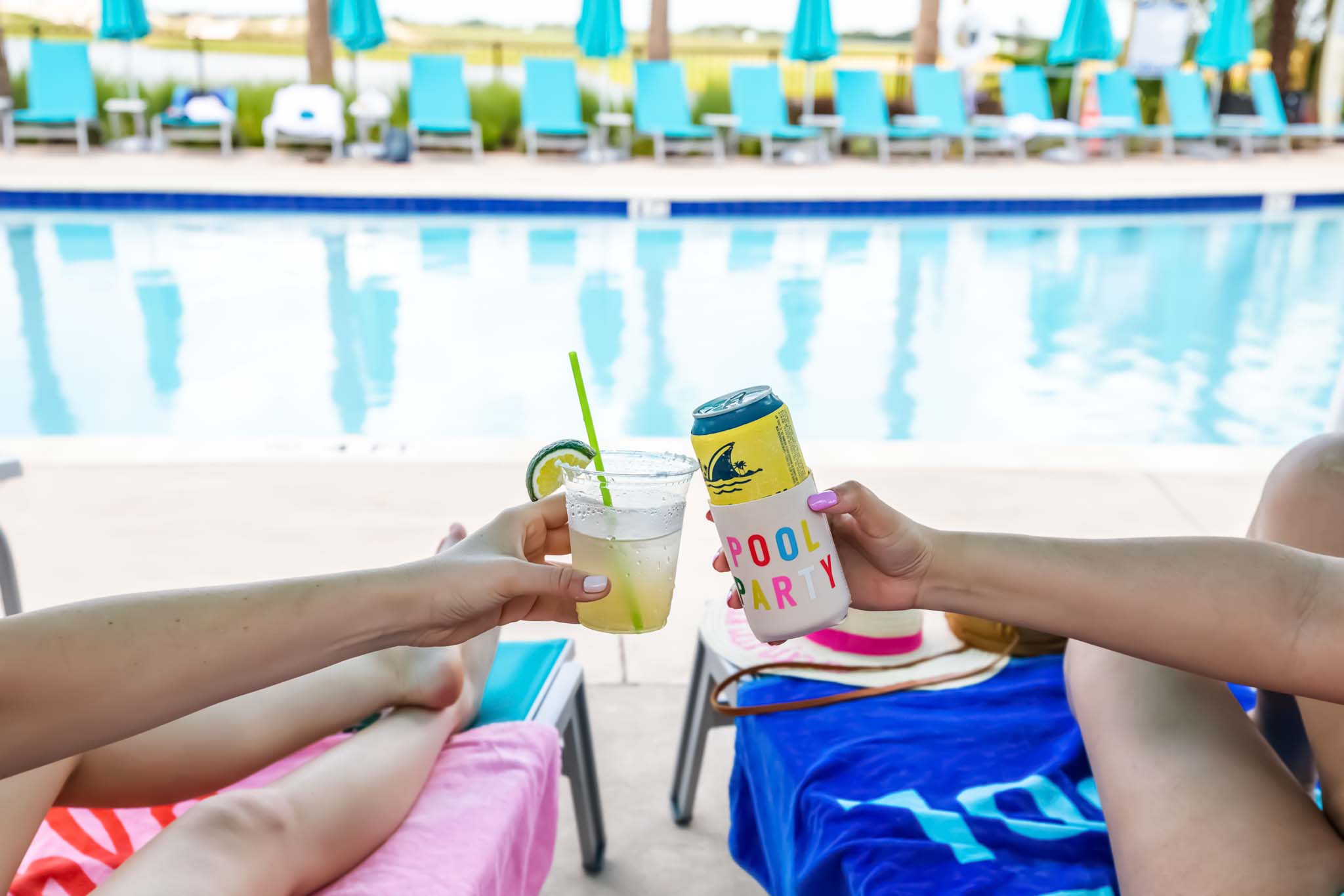 Hands holding tropical drinks by the Margaritaville Resort Orlando pool.
