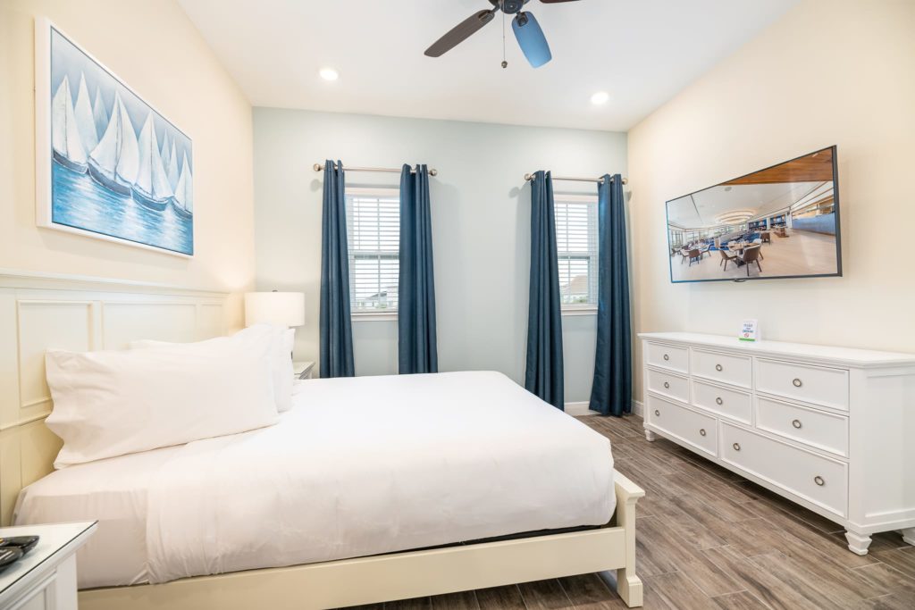 سرير كبير بحجم كينغ يواجه تلفزيونًا مثبتًا على الحائط في غرفة نوم نظيفة: كوخ من 3 غرف نوم ووترز إيدج