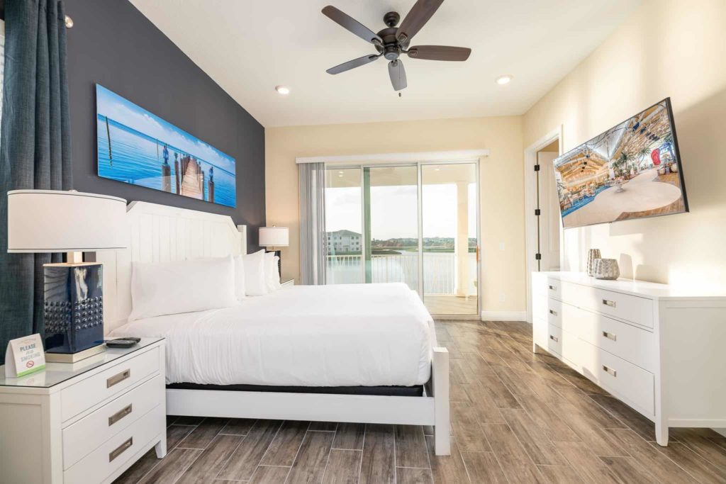 Bedroom with large king bed, TV, and balcony access: 3 Bedroom Waters Edge Cottage
