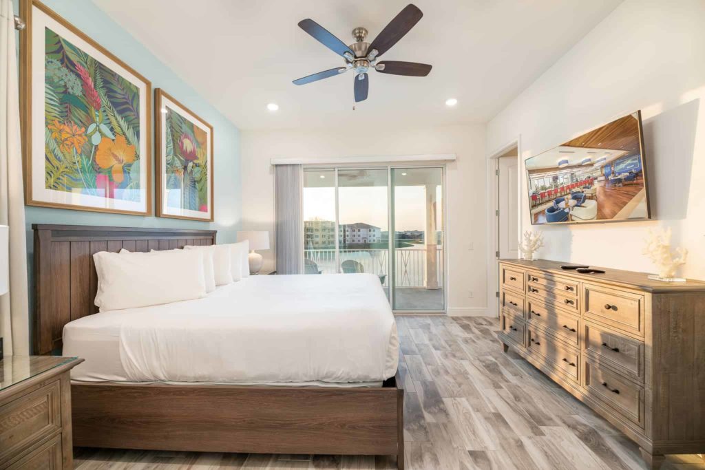 Bedroom with large king bed, TV, and balcony access and views: 3 Bedroom Waters Edge Cottage