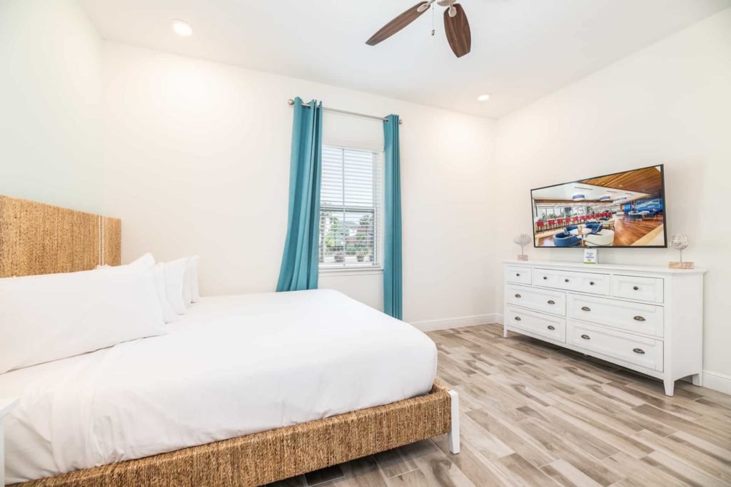 غرفة نوم رئيسية مع سرير كينج كبير وتلفزيون معلق: 2 Bedroom Water's Edge Cottage