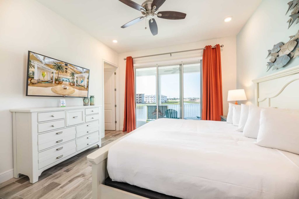 Large king bedroom suite with mounted TV and balcony access: 2 Bedroom Water’s Edge Cottage