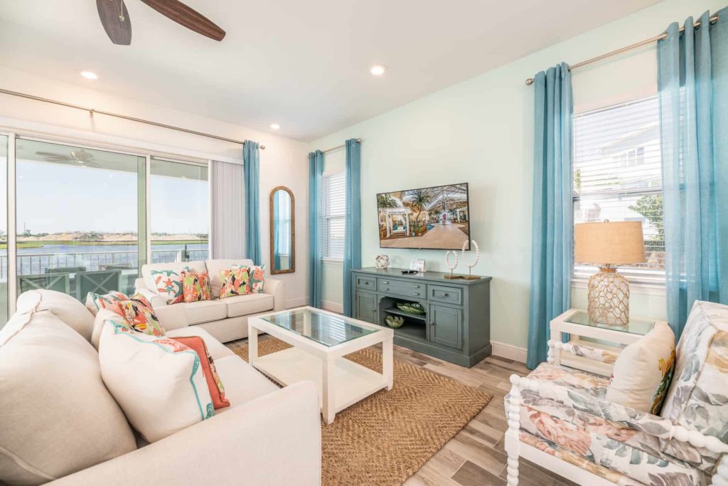 Living room with TV and balcony access: 2 Bedroom Water’s Edge Cottage