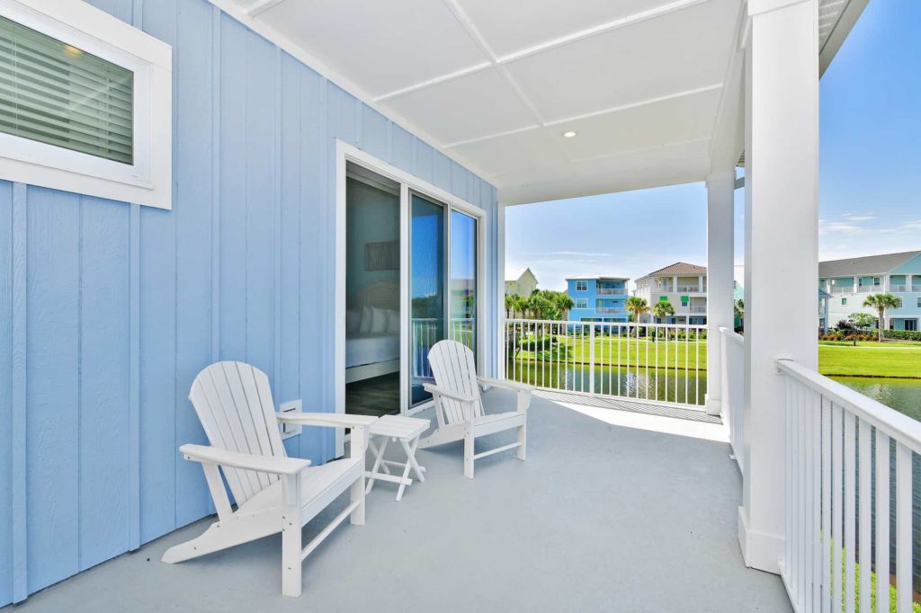 Covered balcony overlooking the water: 3 Bedroom Water’s Edge Cottage with Pool