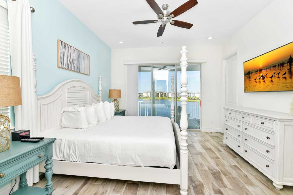 Master bedroom with 4-poster bed, TV, and balcony access: 3 Bedroom Water’s Edge Cottage with Pool