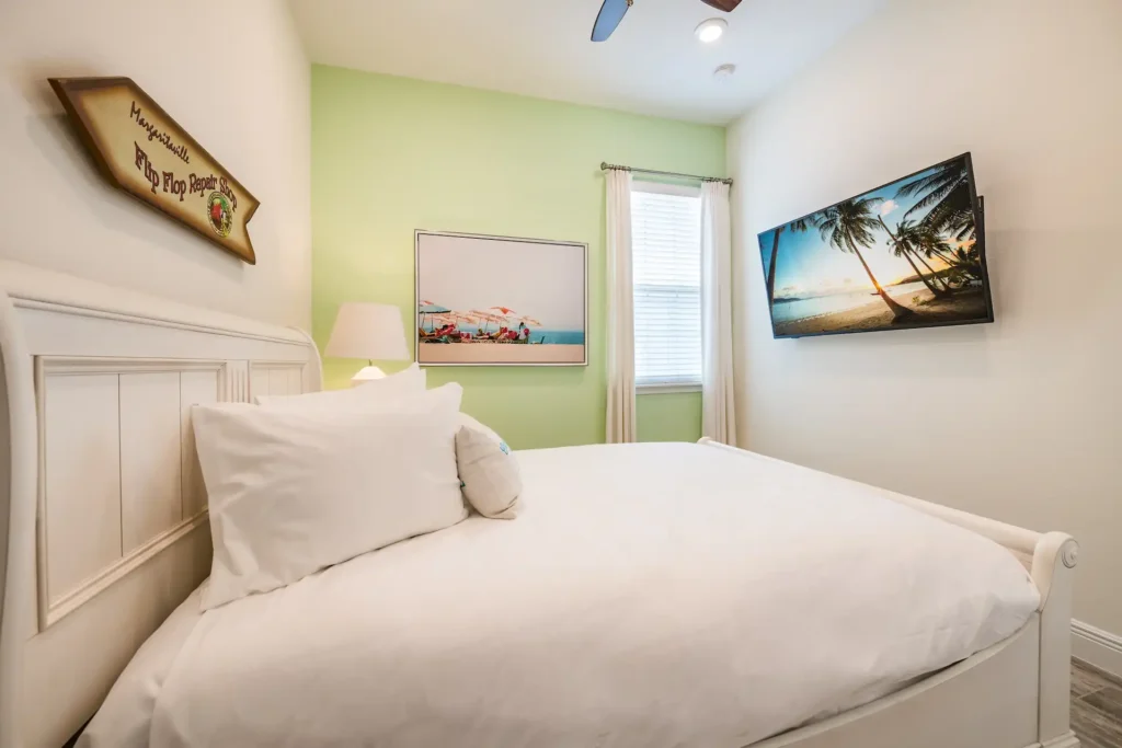 Bedroom 2 with queen bed, wall-mounted TV, and island-inspired wall decor: 3 Bedroom Premium Cottage