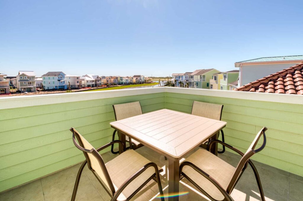 Upper-level outdoor balcony with dining table overlooking Margaritaville Cottages: 4 Bedroom Elite Cottage