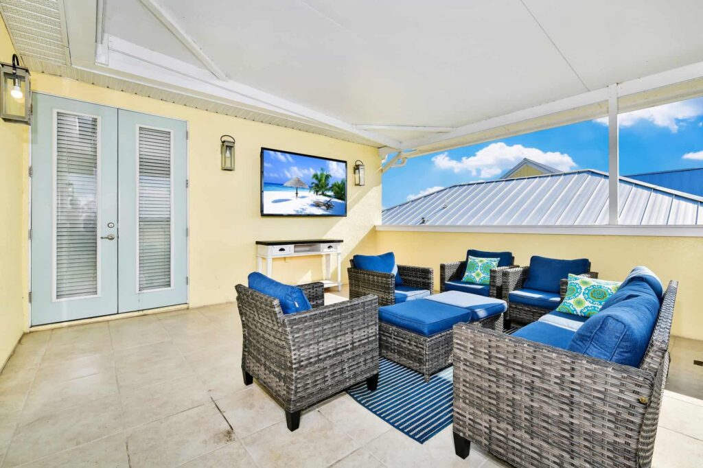 شرفة علوية مغطاة بمقاعد مبطنة وتلفاز معلق على الحائط: منزل ريفي مكون من 7 غرف نوم