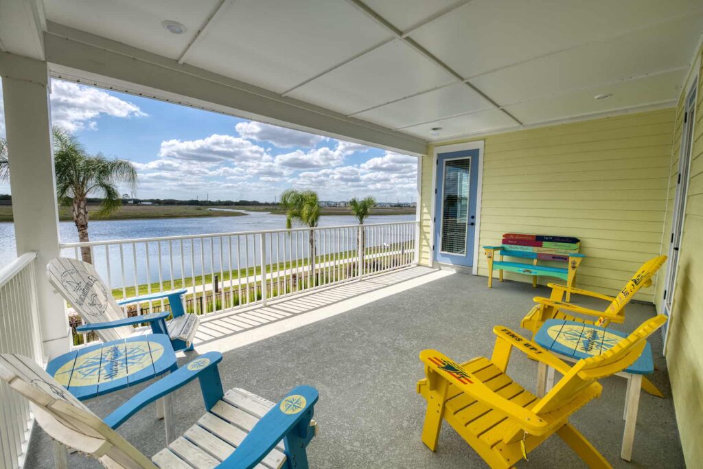 Covered balcony with Adirondack deck chairs and waterfront view: 8 Bedroom Premium Cottage