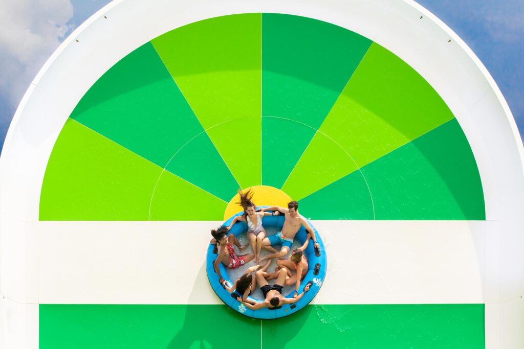 Sechs Personen fahren in einer großen Röhre eine Rampe auf einer Island H2O Live-Wasserrutsche hinauf.