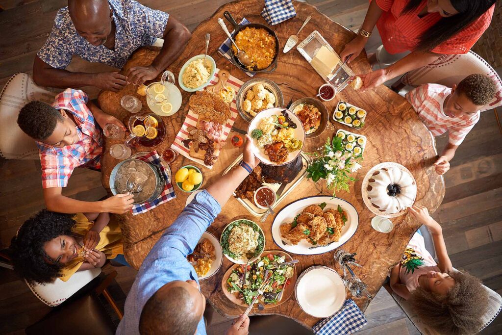 Vue aérienne d'une famille dégustant une table pleine de plats réconfortants du sud au Art Smith's Homecomin' à Disney Springs