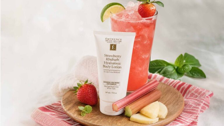 Strawberry Rhubarb Body Lotion on a wooden plate with fruit and a pink cocktail
