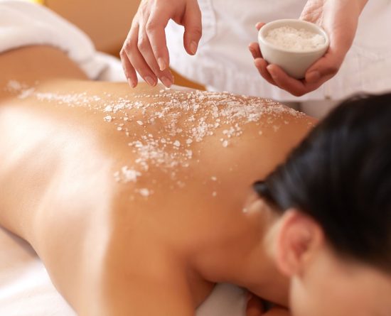 Woman with sugar scrub on her back during a spa treatment.