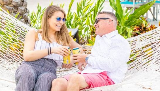 Couple sitting on a hammock holding drinks outside the Salty Rim Bar and Grill.