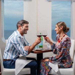 زوجان يستمتعان بالنبيذ في عشاءهما الخاص مع إطلالات على المحيط
